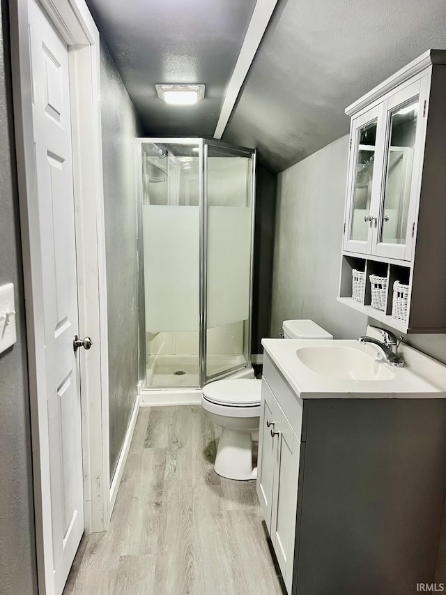 bathroom featuring toilet, a shower with shower door, a textured ceiling, vanity, and hardwood / wood-style floors