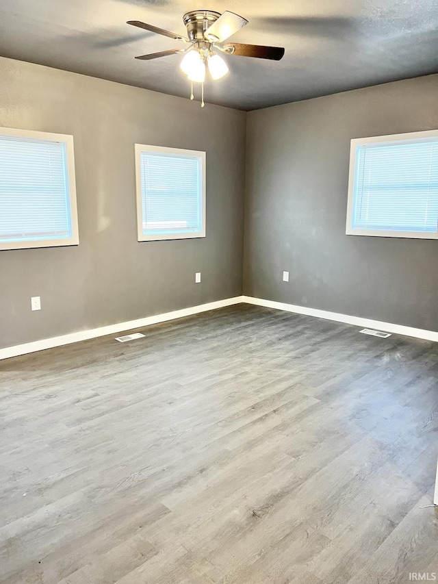 unfurnished room with ceiling fan, a healthy amount of sunlight, and light wood-type flooring