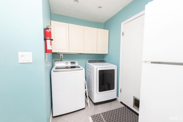 washroom featuring cabinets, a textured ceiling, and independent washer and dryer