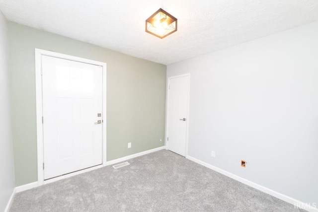 empty room featuring light colored carpet and a textured ceiling