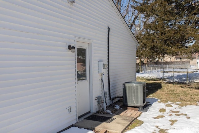 snow covered property entrance featuring central air condition unit