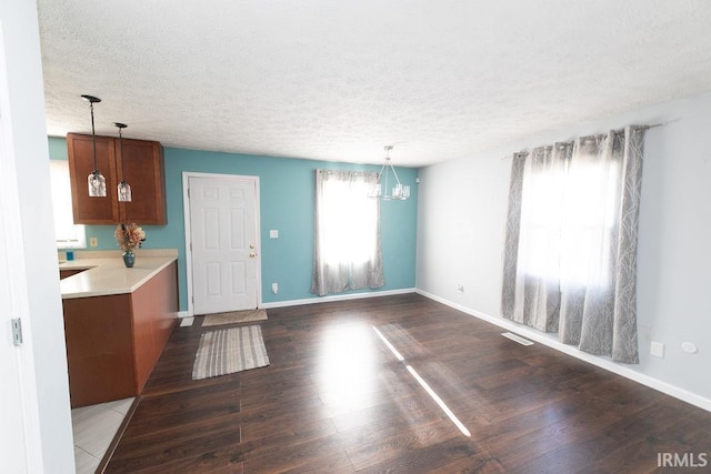 unfurnished living room with dark hardwood / wood-style floors, an inviting chandelier, and a textured ceiling