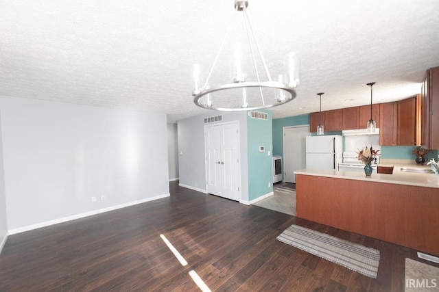 kitchen featuring sink, dark hardwood / wood-style floors, a textured ceiling, decorative light fixtures, and white fridge