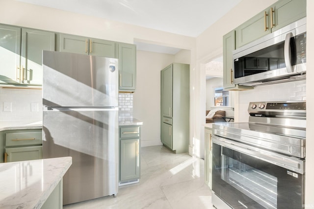 kitchen with light stone counters, green cabinets, decorative backsplash, and appliances with stainless steel finishes