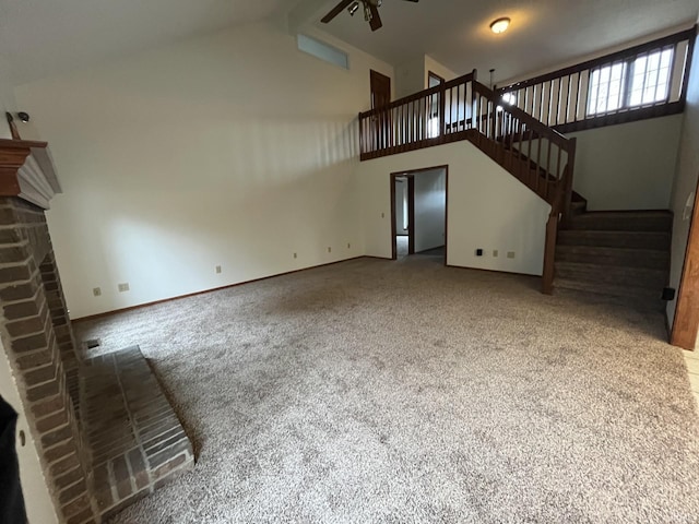 unfurnished living room featuring ceiling fan, high vaulted ceiling, carpet, and a brick fireplace