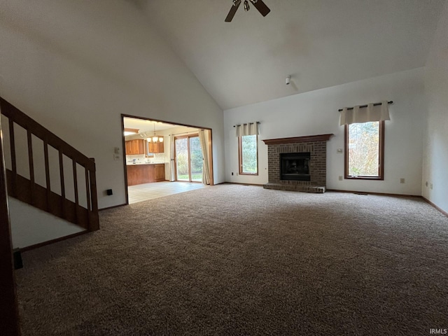 unfurnished living room with ceiling fan, a brick fireplace, carpet floors, and high vaulted ceiling