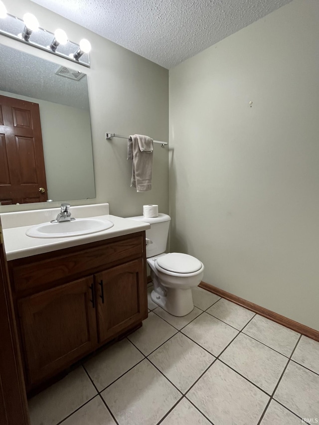 bathroom with tile patterned flooring, vanity, a textured ceiling, and toilet