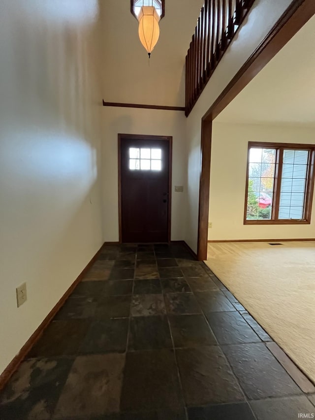 entryway featuring dark colored carpet and a towering ceiling