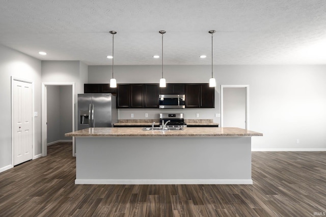 kitchen featuring stainless steel appliances, an island with sink, pendant lighting, and a textured ceiling