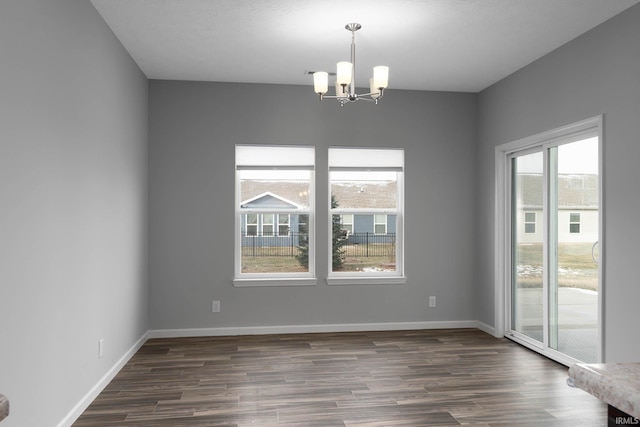 empty room featuring dark wood-type flooring and an inviting chandelier