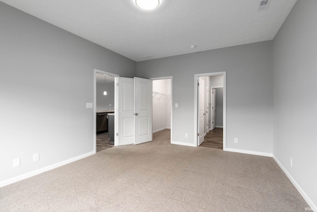 unfurnished bedroom with a spacious closet, dark carpet, and a closet