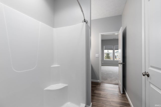 bathroom featuring hardwood / wood-style flooring, a textured ceiling, and walk in shower