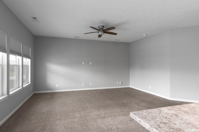 carpeted empty room featuring ceiling fan and a textured ceiling