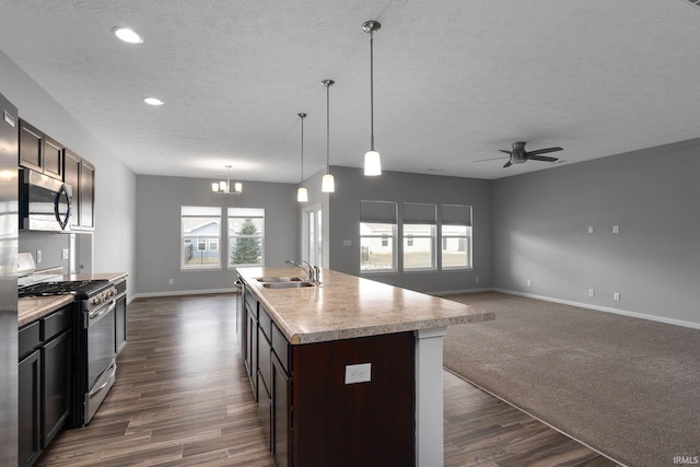 kitchen with appliances with stainless steel finishes, sink, dark hardwood / wood-style flooring, a kitchen island with sink, and dark brown cabinets