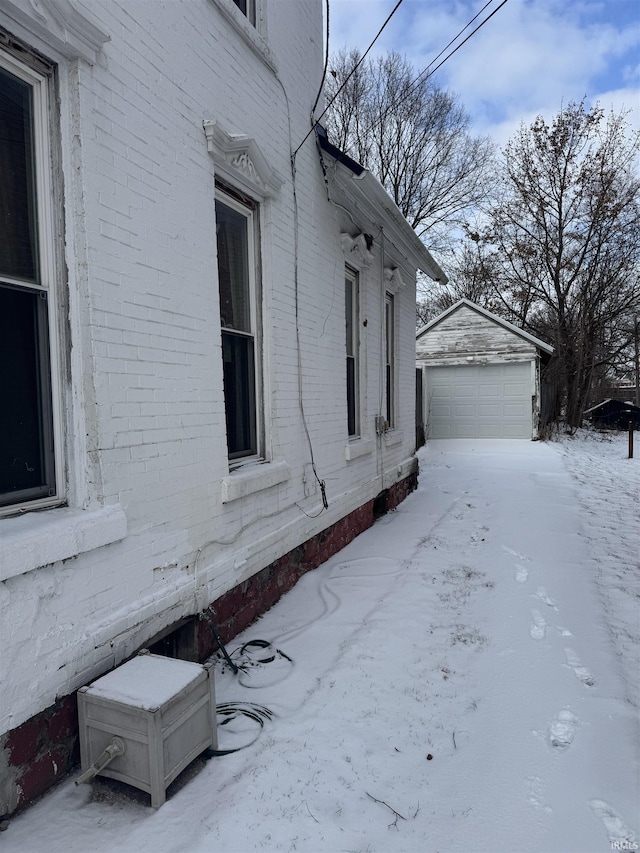 view of snowy exterior featuring a garage and an outdoor structure