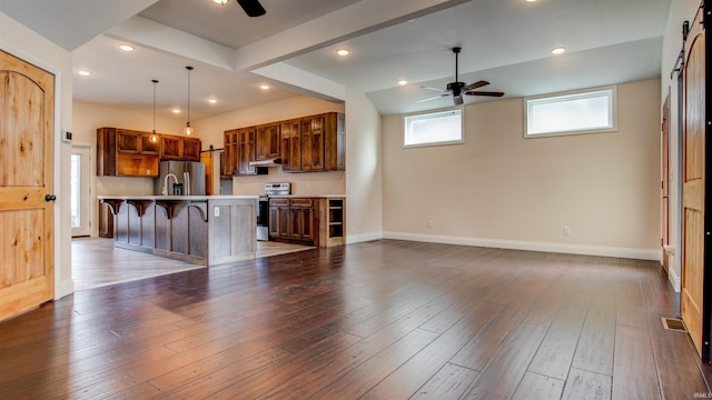 kitchen with stainless steel appliances, ceiling fan, hanging light fixtures, and a kitchen bar