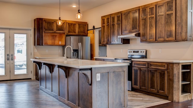 kitchen with hardwood / wood-style floors, hanging light fixtures, a kitchen island with sink, stainless steel appliances, and french doors