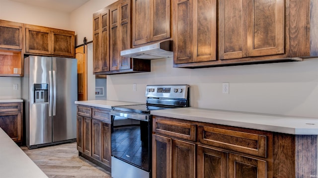 kitchen featuring stainless steel appliances, a barn door, and light hardwood / wood-style floors