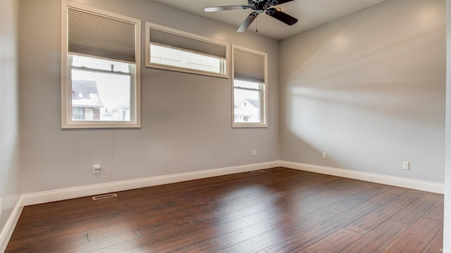 spare room with dark wood-type flooring, plenty of natural light, and ceiling fan