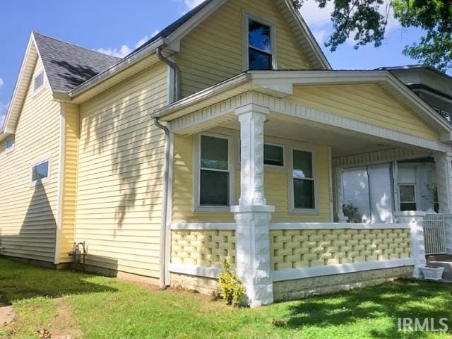 view of home's exterior with a porch and a lawn