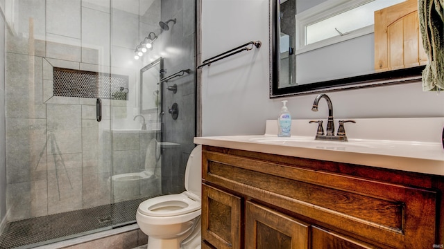 bathroom with vanity, a shower with door, and toilet