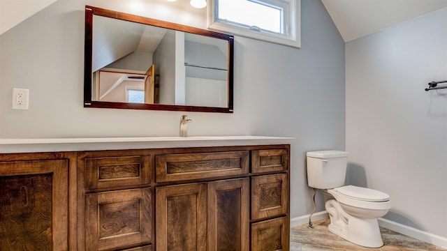 bathroom featuring hardwood / wood-style flooring, vanity, toilet, and vaulted ceiling