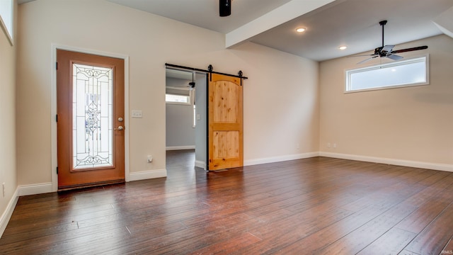 foyer entrance featuring dark hardwood / wood-style floors, ceiling fan, a barn door, and beamed ceiling