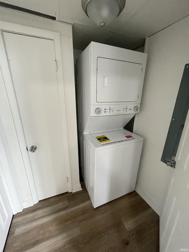 laundry area with stacked washer and dryer and dark wood-type flooring