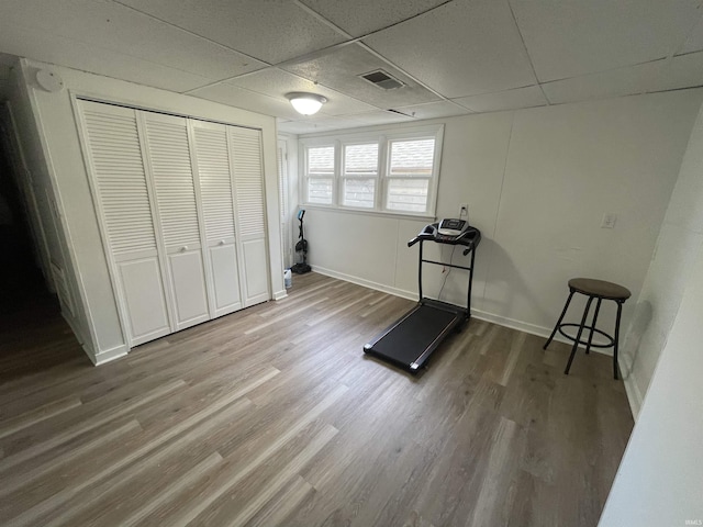 exercise room featuring a paneled ceiling and wood-type flooring