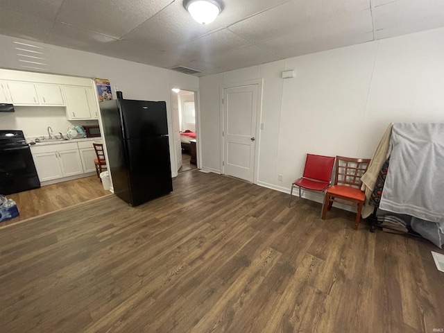 kitchen with dark hardwood / wood-style floors, sink, white cabinets, black appliances, and a drop ceiling