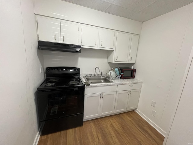 kitchen with black electric range oven, sink, white cabinetry, a drop ceiling, and light wood-type flooring