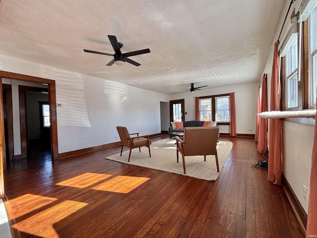 living room with ceiling fan, dark hardwood / wood-style flooring, and a textured ceiling