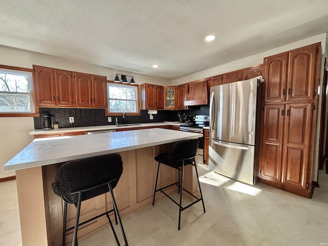 kitchen with appliances with stainless steel finishes, a center island, sink, and a kitchen bar