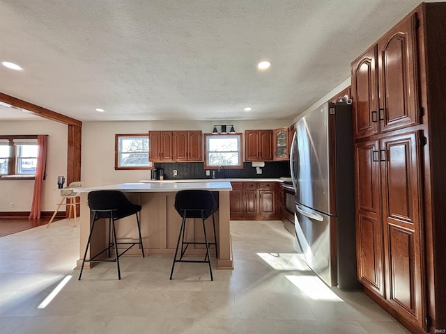 kitchen featuring sink, a kitchen breakfast bar, a kitchen island, stainless steel appliances, and decorative backsplash