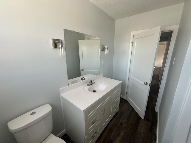 bathroom featuring wood-type flooring, toilet, a textured ceiling, and vanity