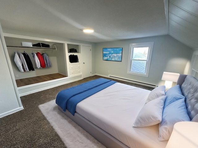 bedroom featuring lofted ceiling, dark carpet, baseboard heating, and a closet