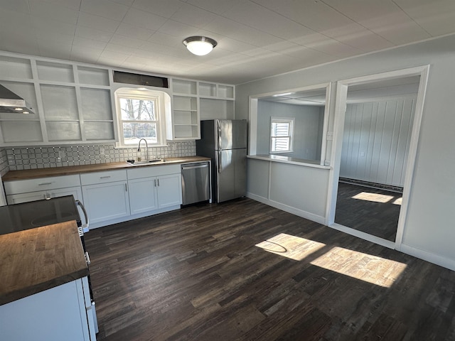 kitchen with appliances with stainless steel finishes, butcher block counters, sink, white cabinets, and plenty of natural light