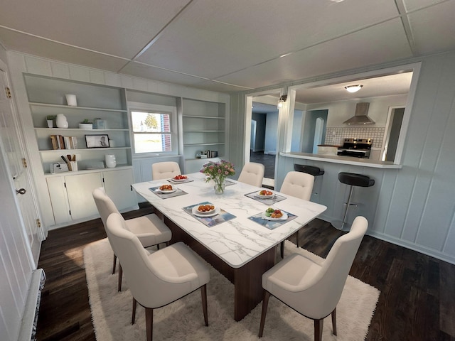 dining area with a baseboard heating unit, built in features, and dark hardwood / wood-style flooring