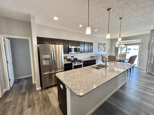 kitchen featuring pendant lighting, appliances with stainless steel finishes, sink, and a center island with sink