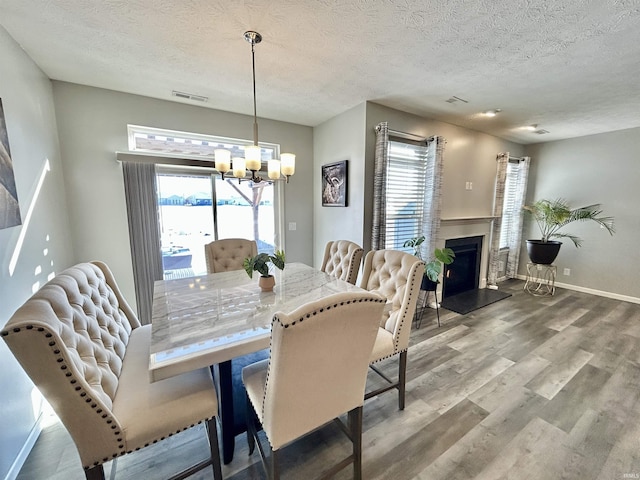 dining area featuring hardwood / wood-style flooring, a water view, a chandelier, and a textured ceiling