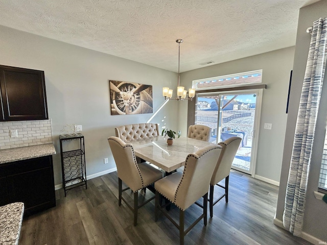 dining room with an inviting chandelier, dark wood-type flooring, and a textured ceiling