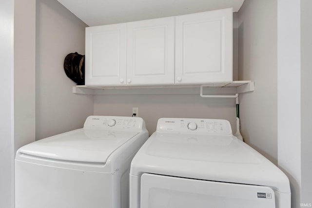 clothes washing area featuring washing machine and dryer and cabinets