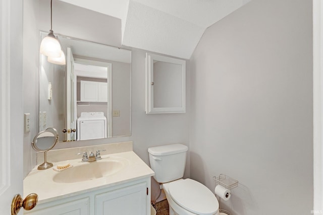 bathroom with washer / clothes dryer, vanity, vaulted ceiling, and toilet