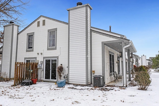 snow covered back of property with central AC