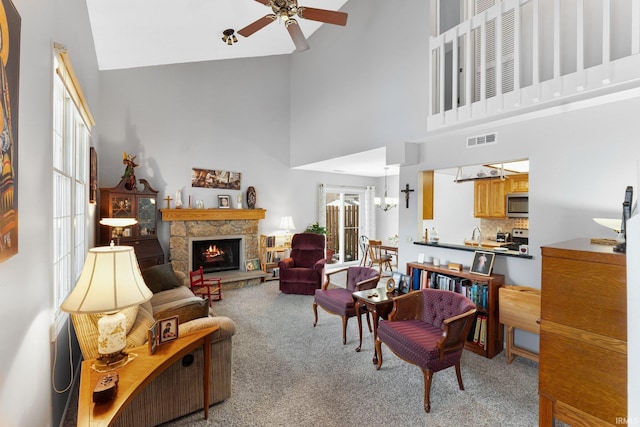 living room featuring light carpet, a fireplace, high vaulted ceiling, and ceiling fan