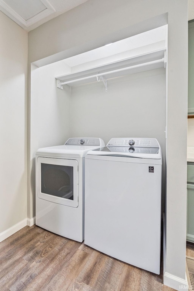 clothes washing area featuring wood-type flooring and independent washer and dryer