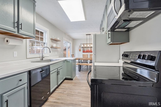 kitchen featuring electric stove, dishwasher, sink, hanging light fixtures, and light hardwood / wood-style flooring