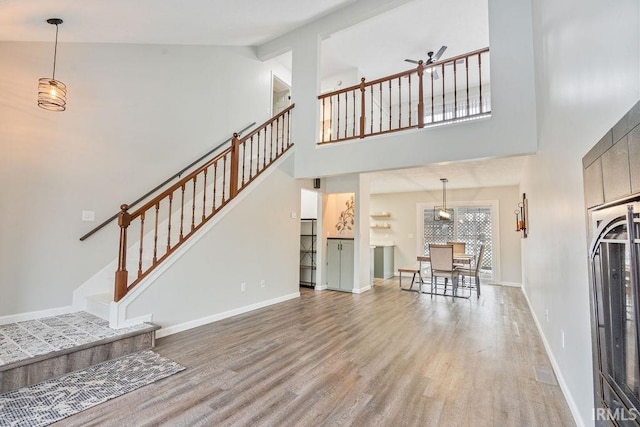 unfurnished living room featuring wood-type flooring, high vaulted ceiling, and ceiling fan