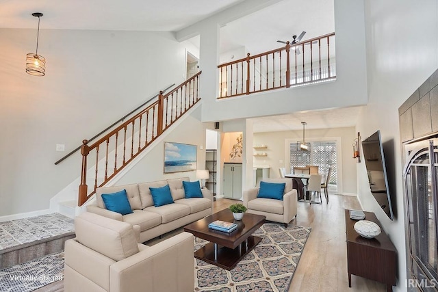 living room with ceiling fan, high vaulted ceiling, and light hardwood / wood-style floors