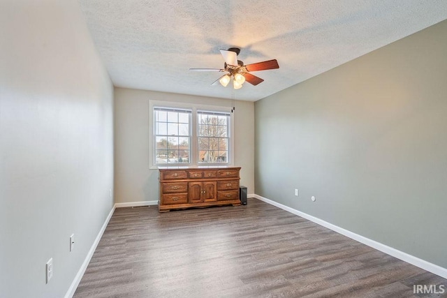 empty room with ceiling fan, wood-type flooring, and a textured ceiling